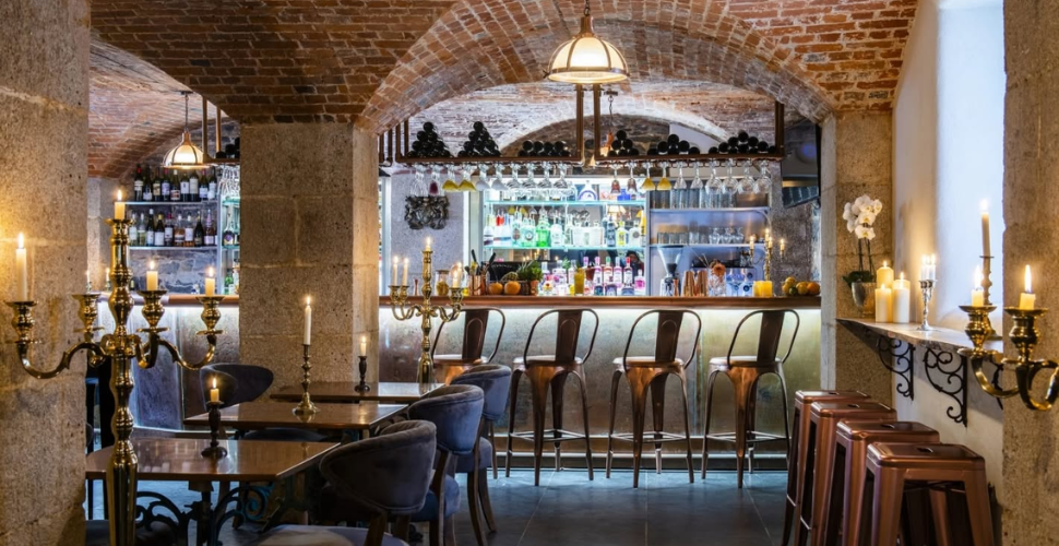 A candlelit cellar bar with brick vaulted ceilings, high stools, and a stocked counter. A candlelit cellar bar with brick vaulted ceilings, high stools, and a stocked counter.